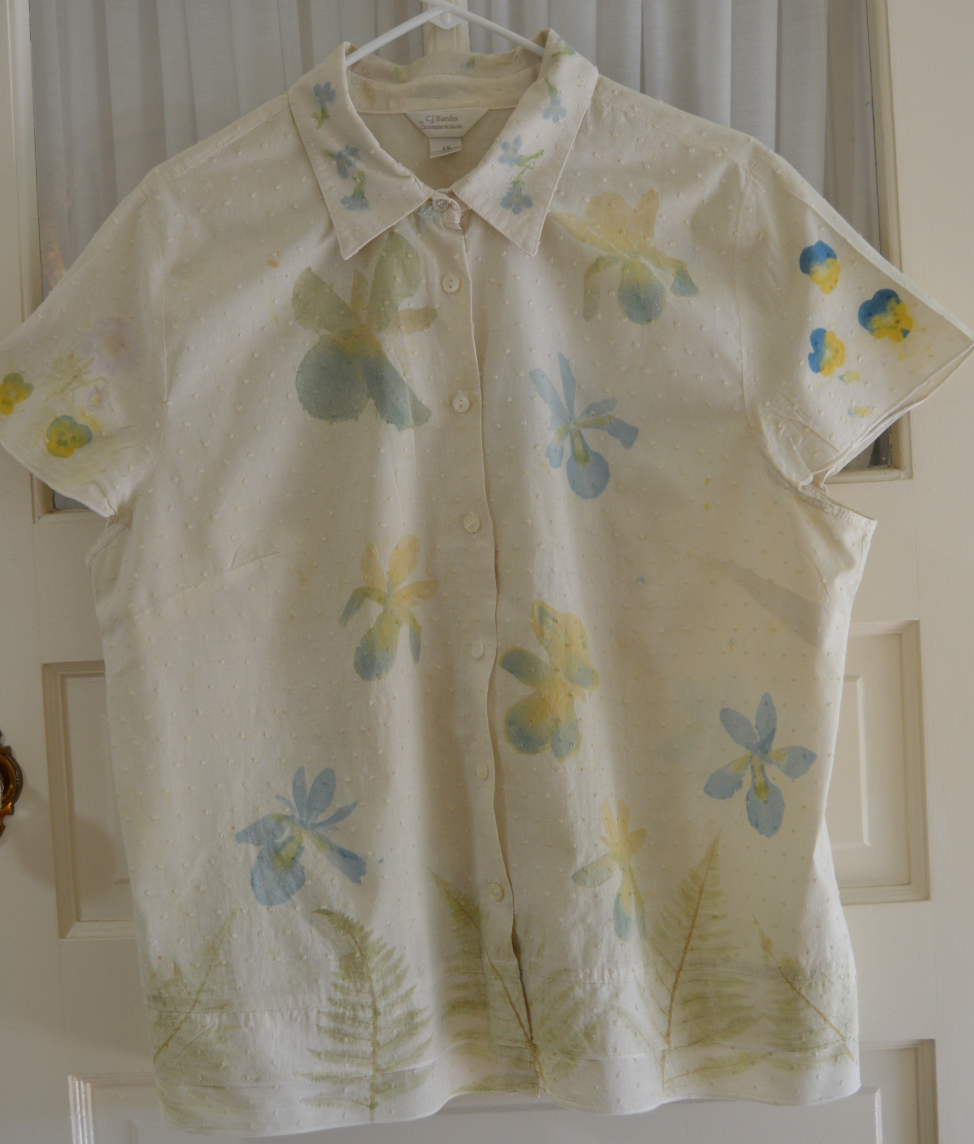 Front of a cream Swiss dot cotton blouse pounded with blue and yellow irises and green fern motifs